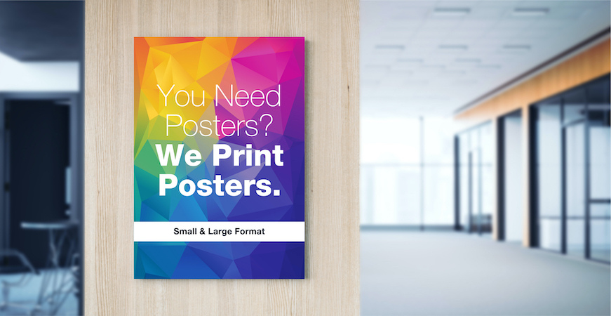 The inside of a well-lit modern office with a poster on a divider wall that says, “You Need Posters? We Print Posters. Small & Large Format.”